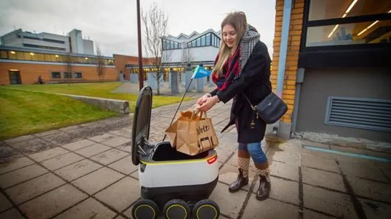 Starship toob toidu TTÜ-sse. Diana Makhova, Tallinna Tehnikaülikooli tudeng, vastu võtmas oma esimest roboti poolt kohaletoimetatud Wolti tellimust.